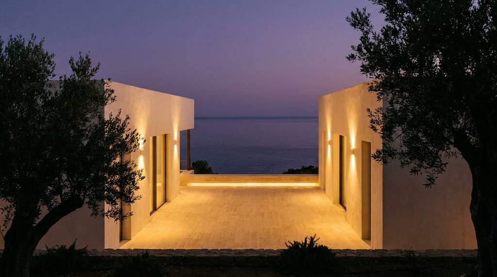 Villa face à la Méditerranée, projet sur mesure Villa contemporaine au crépuscule face à la Méditerranée, terrasse en travertin éclairée chaud, mer calme à l'horizon, ciel pourpre, ambiance de fin de journée d'été